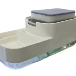 Dispensador de jabón Tama en color crema con base transparente y esponja azul sobre tapa superior, visto desde ángulo lateral.