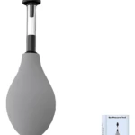 Dispositivo de presión neumática para oídos en color gris, con mango negro y bolsa inflable, acompañado de su caja y accesorio de limpieza.