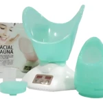 Vaporizador facial en color menta, con base blanca y panel digital, acompañado de su tapa y caja de presentación.