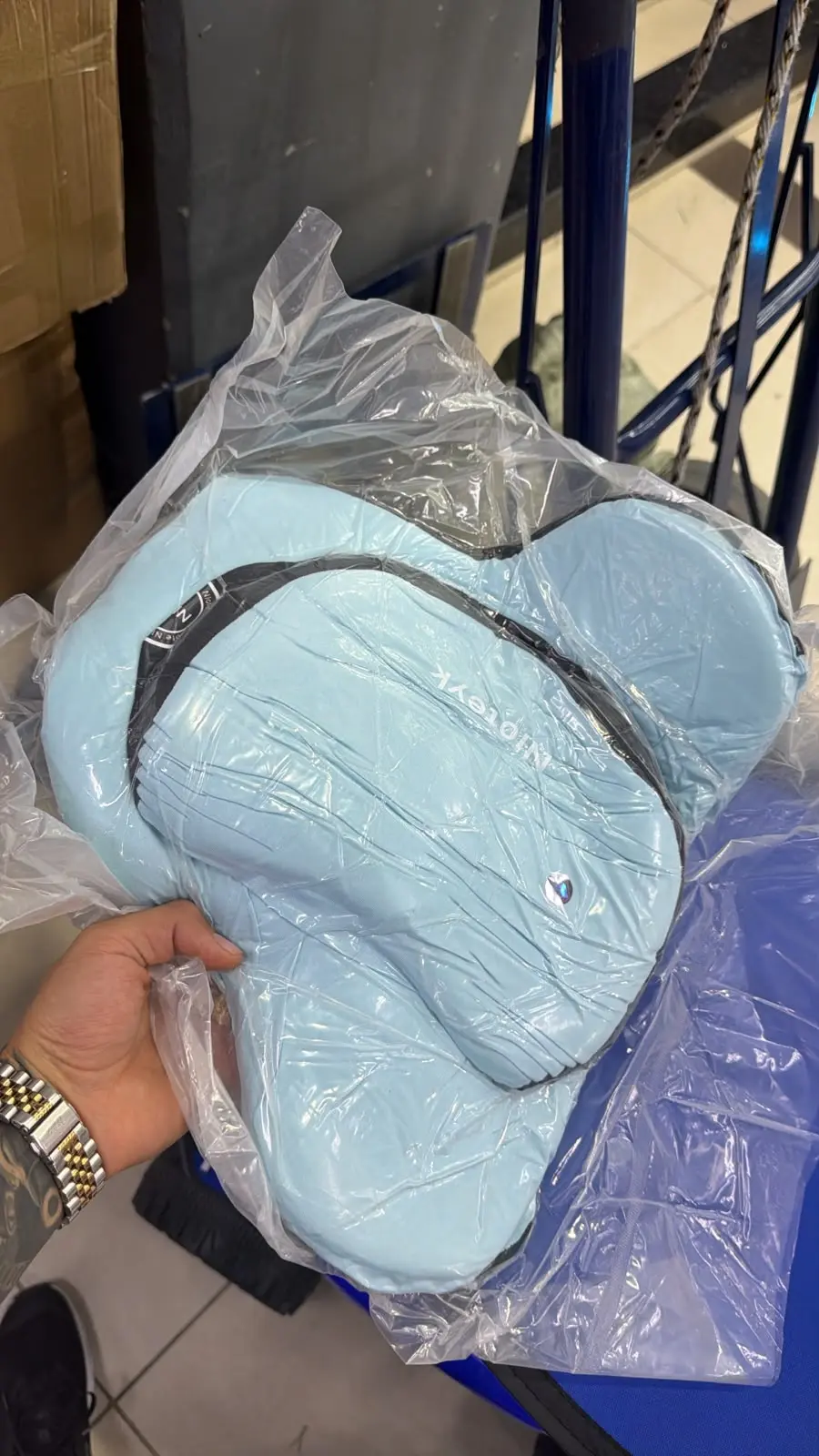 Kit de almohada para cuello y cojín lumbar viscoelástico azul claro, empacados en plástico transparente, con diseño ergonómico para viajes.