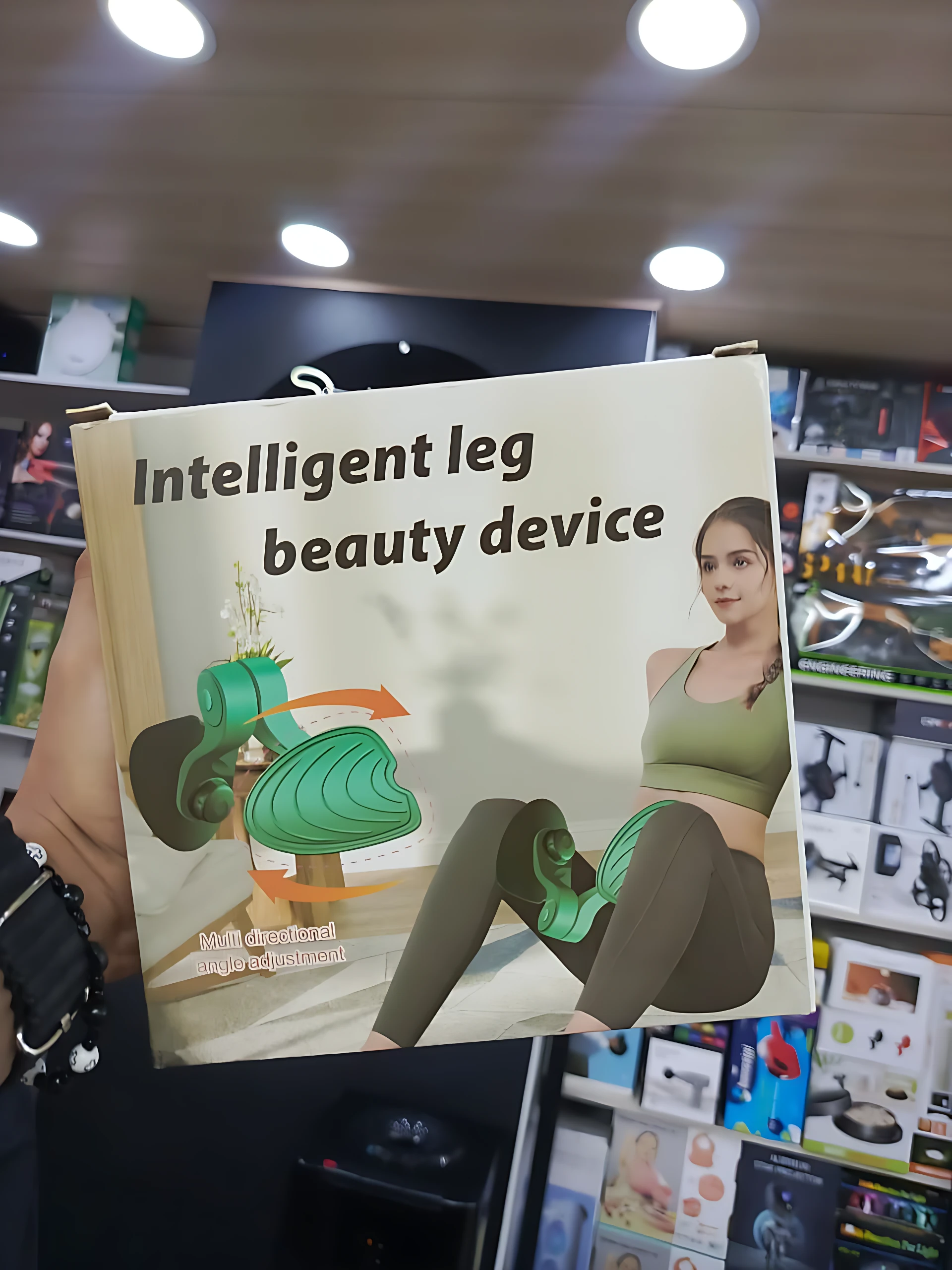 Caja del Ejercitador de Piernas y Cadera Ergonómico, mostrando de uso con mujer sentada y diagrama de funcionamiento en tonos verdes y marrones.