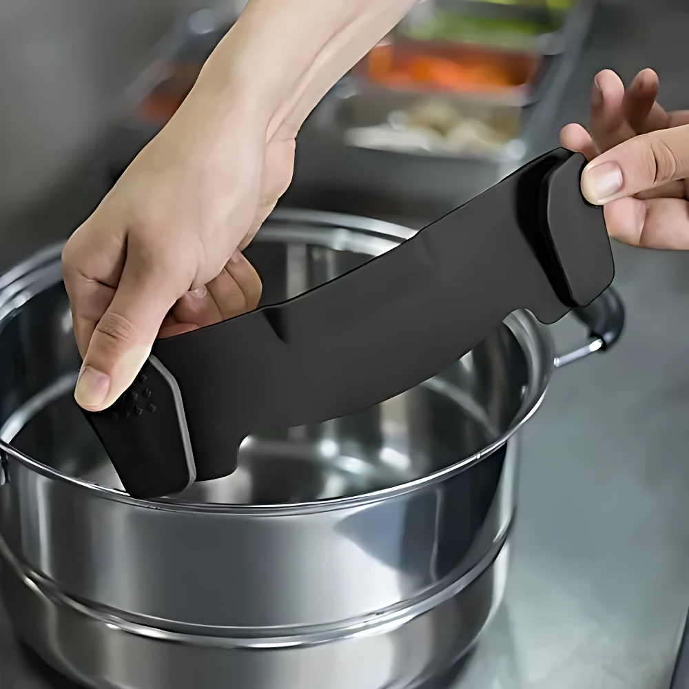 Escurridor de pasta negro con soporte para olla, siendo colocado sobre recipiente metálico en cocina.