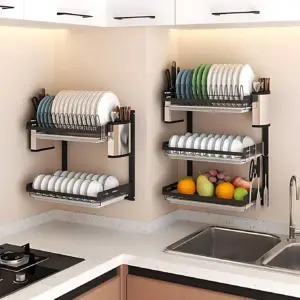 Estante de acero inoxidable de tres niveles, montado en pared de cocina, con platos, frutas y cubiertos organizados en cada estante.