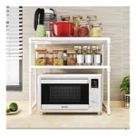 Estante blanco de tres niveles para horno, con estanterías superiores cargadas de recipientes y especieros, sobre horno microondas en cocina.