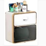 Dispensador de papel higiénico blanco con detalles dorados, incluye estante superior para accesorios de baño.