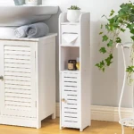 Estante vertical blanco para baño, con estantes abiertos y cajón inferior, ubicado junto a lavandería.