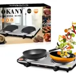Estufa eléctrica Sokany de dos quemadores, con sartenes negras y amarillas sobre superficie metálica brillante; incluye caja de cartón con ilustraciones de comida y vegetales salteados en primer plano.