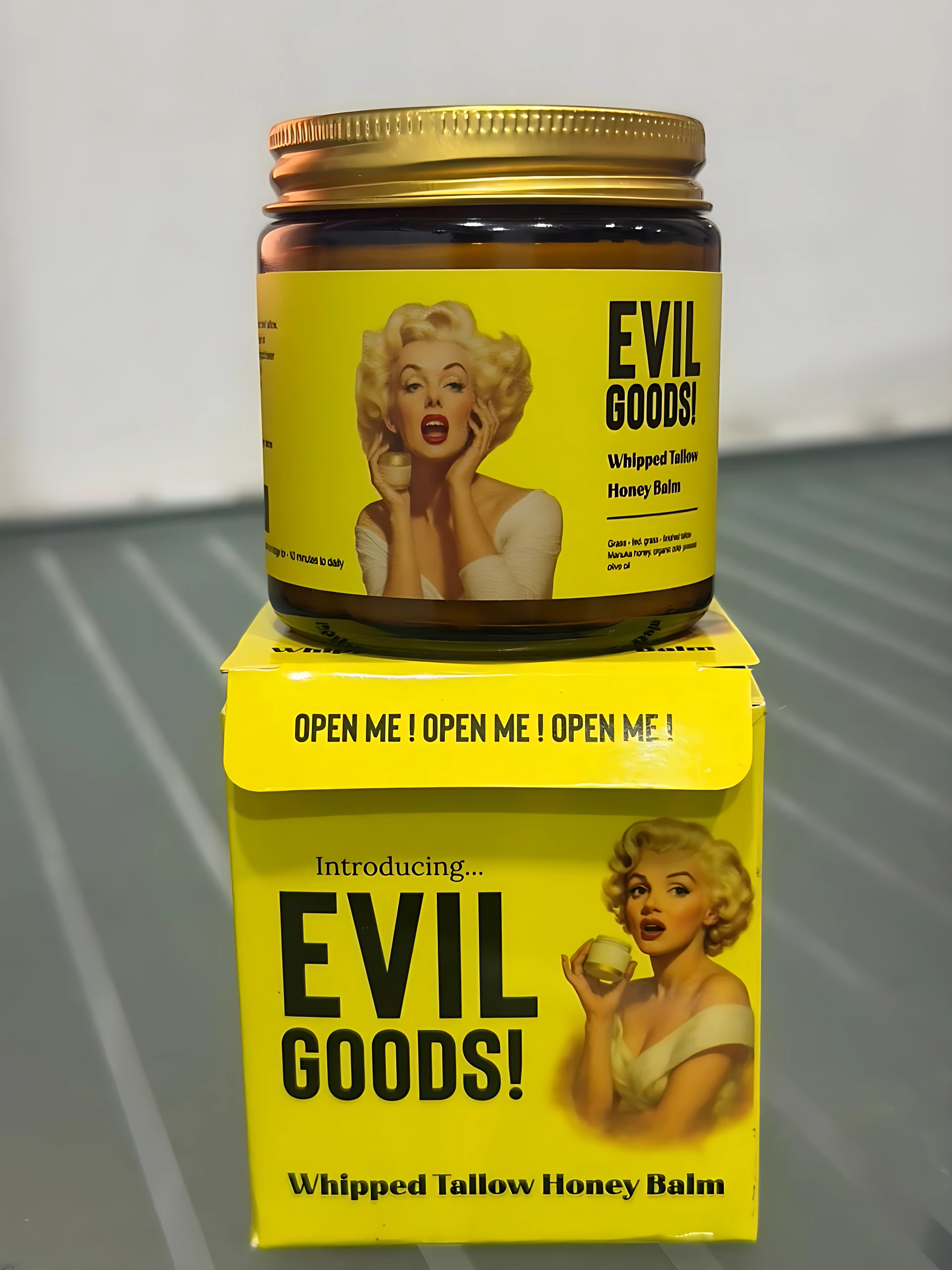 Bálsamo Evil Goods con sebo de res y miel en frasco de vidrio con tapa dorada y etiqueta amarilla con de Marilyn Monroe.