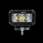 Luz de trabajo rectangular negra con dos focos LED centrales y luces auxiliares rojas y azules laterales, montada sobre soporte metálico con tornillo visible.