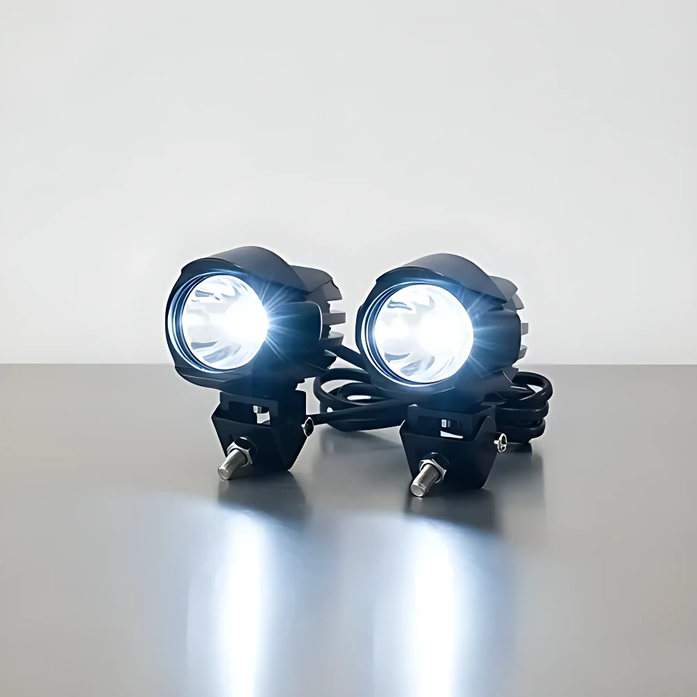 Dos faros LED auxiliares JRY-10 de 100W, color negro, montados sobre superficie gris, emitiendo luz blanca intensa.
