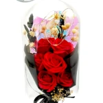Domo de vidrio con arreglo floral de rosas rojas y flores blancas, sobre base negra. Medidas 21 cm de alto por 11 cm de ancho.