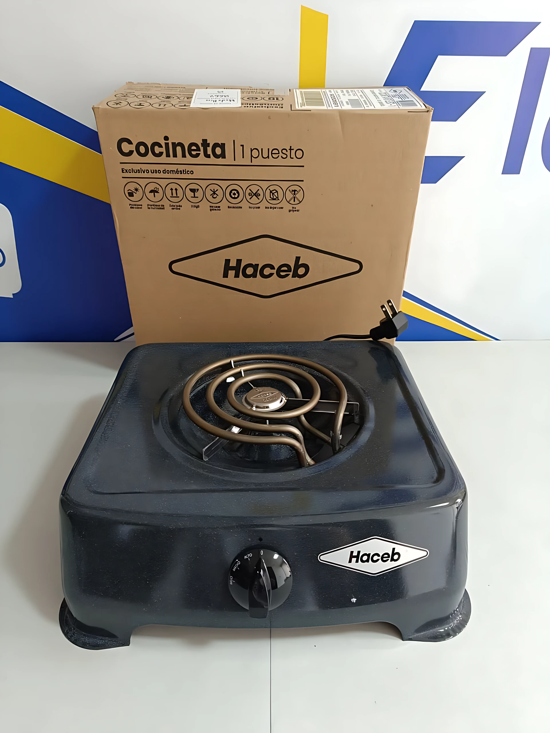 Fogón eléctrico Haceb de un quemador, color azul oscuro, con control de temperatura y caja original al fondo.