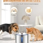 Fuente de agua automática para mascotas en acero inoxidable, con diseño cilíndrico y panel azul frontal. Un perro beagle y un gato naranja beben simultáneamente sobre piso blanco.