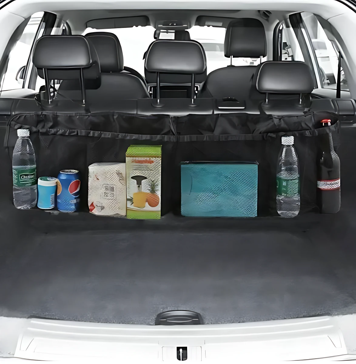 Organizador negro para baúl de camioneta con compartimentos, mostrando botellas, latas y cajas almacenadas tras los asientos traseros.