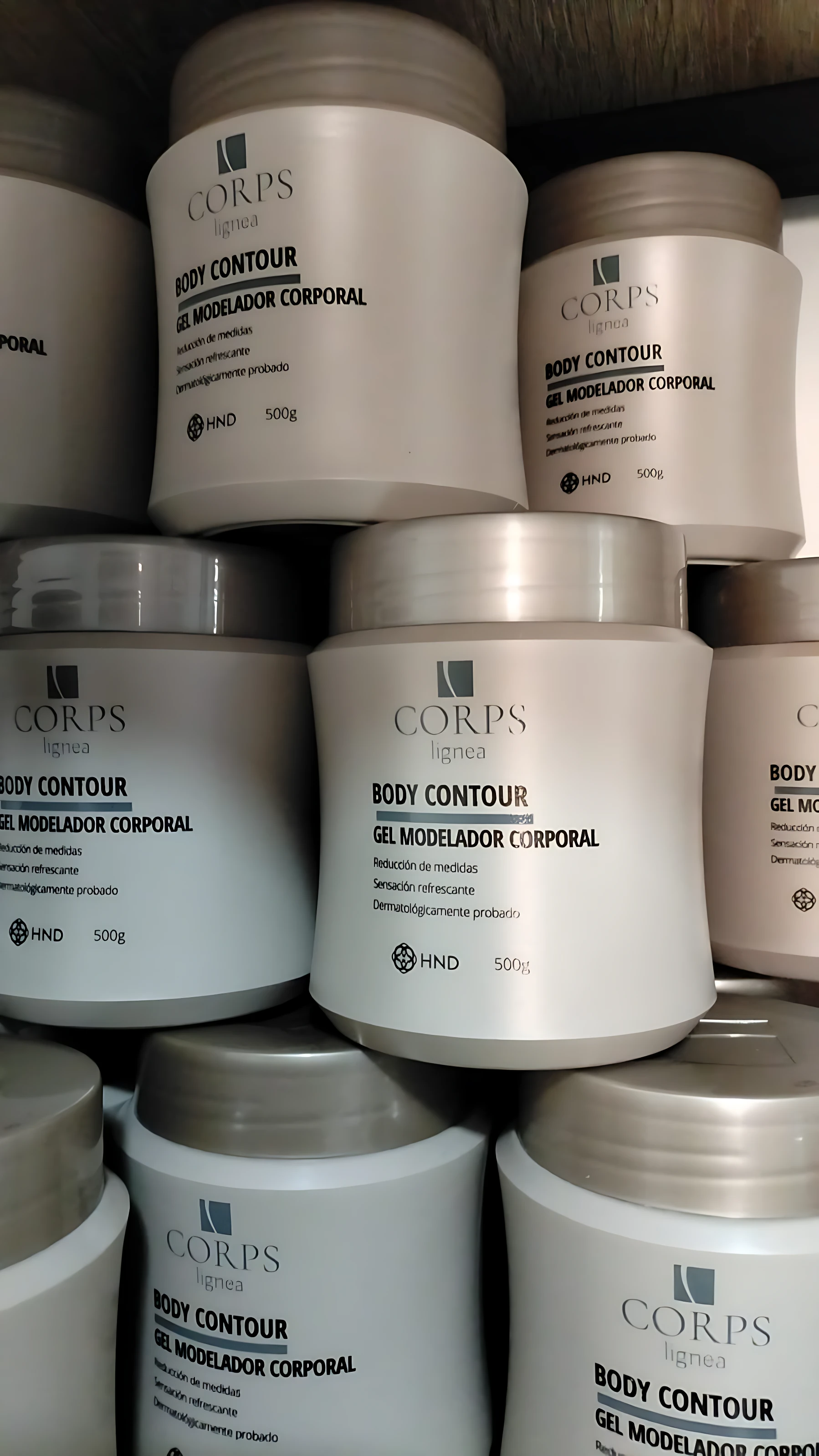 Varios frascos de Gel Moldeador Corporal Corps Lignea con Crioterapia y Mentol, presentados en tonos beige y plateado, apilados en estantería.