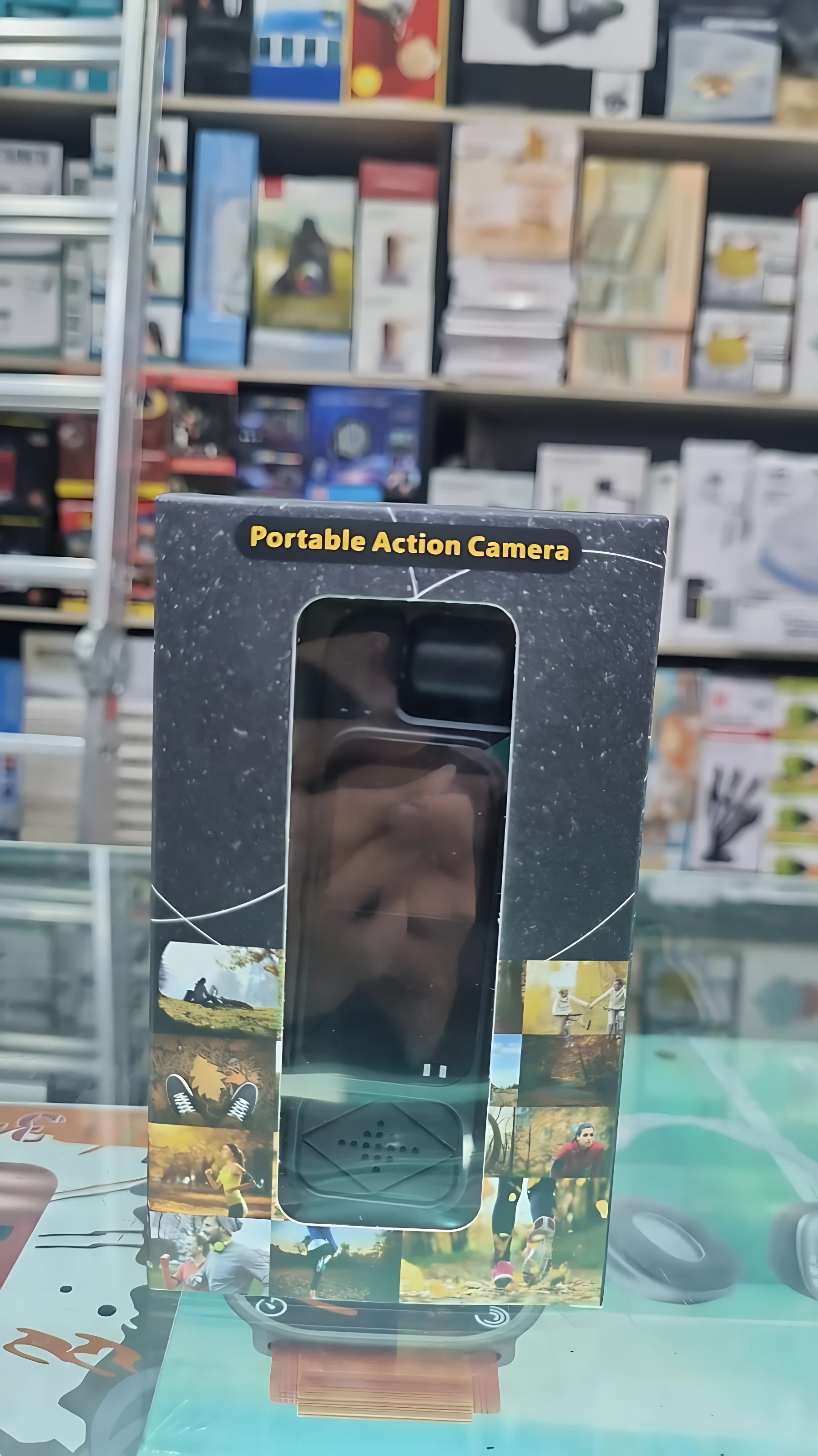Cámara de acción portátil en caja negra con ventana transparente, mostrando dispositivo con pantalla y botón central.