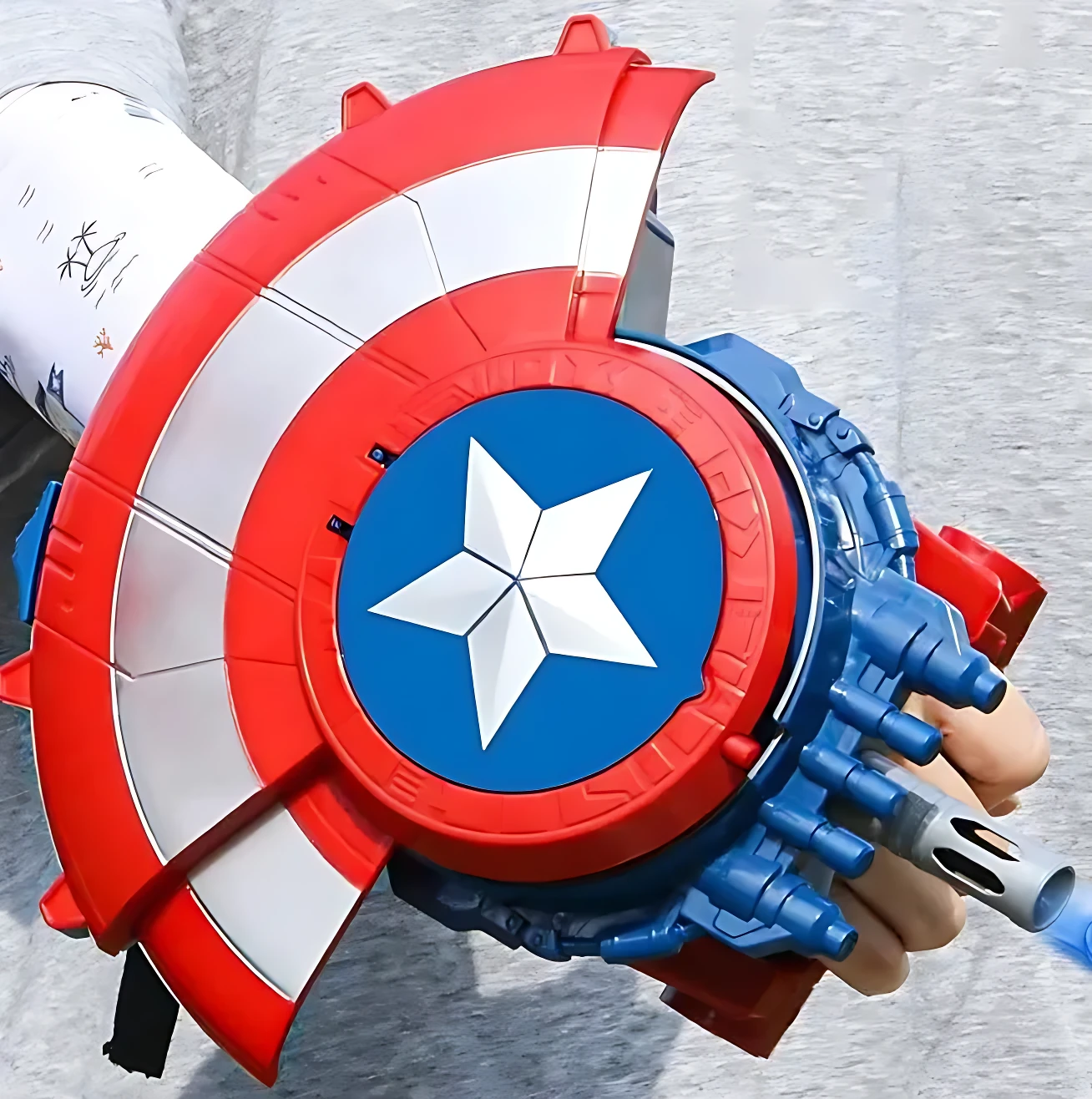 Guante de Capitán América con diseño de escudo, detalles en rojo, blanco y azul, y lanzador de bolitas de hidrogel integrado.