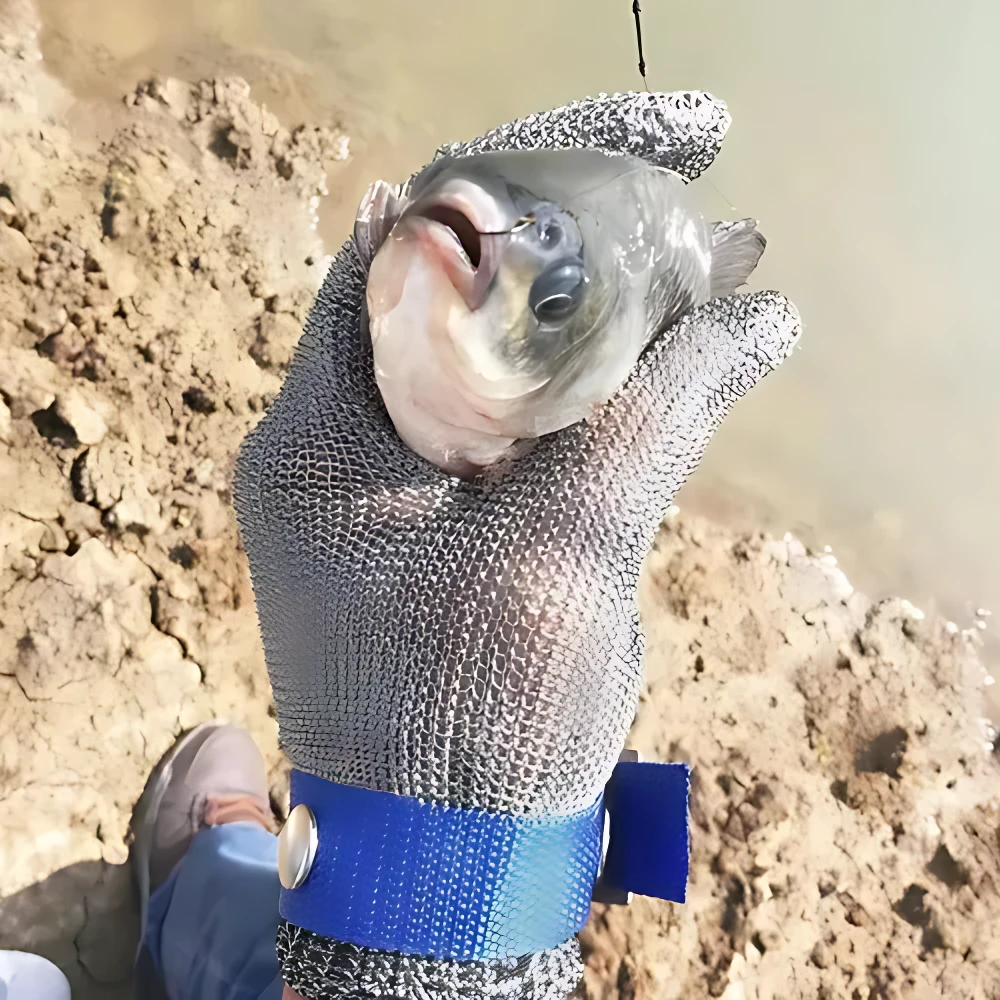 Guante de malla de acero inoxidable con hebilla azul, usado sosteniendo un pez cerca de orilla de río.
