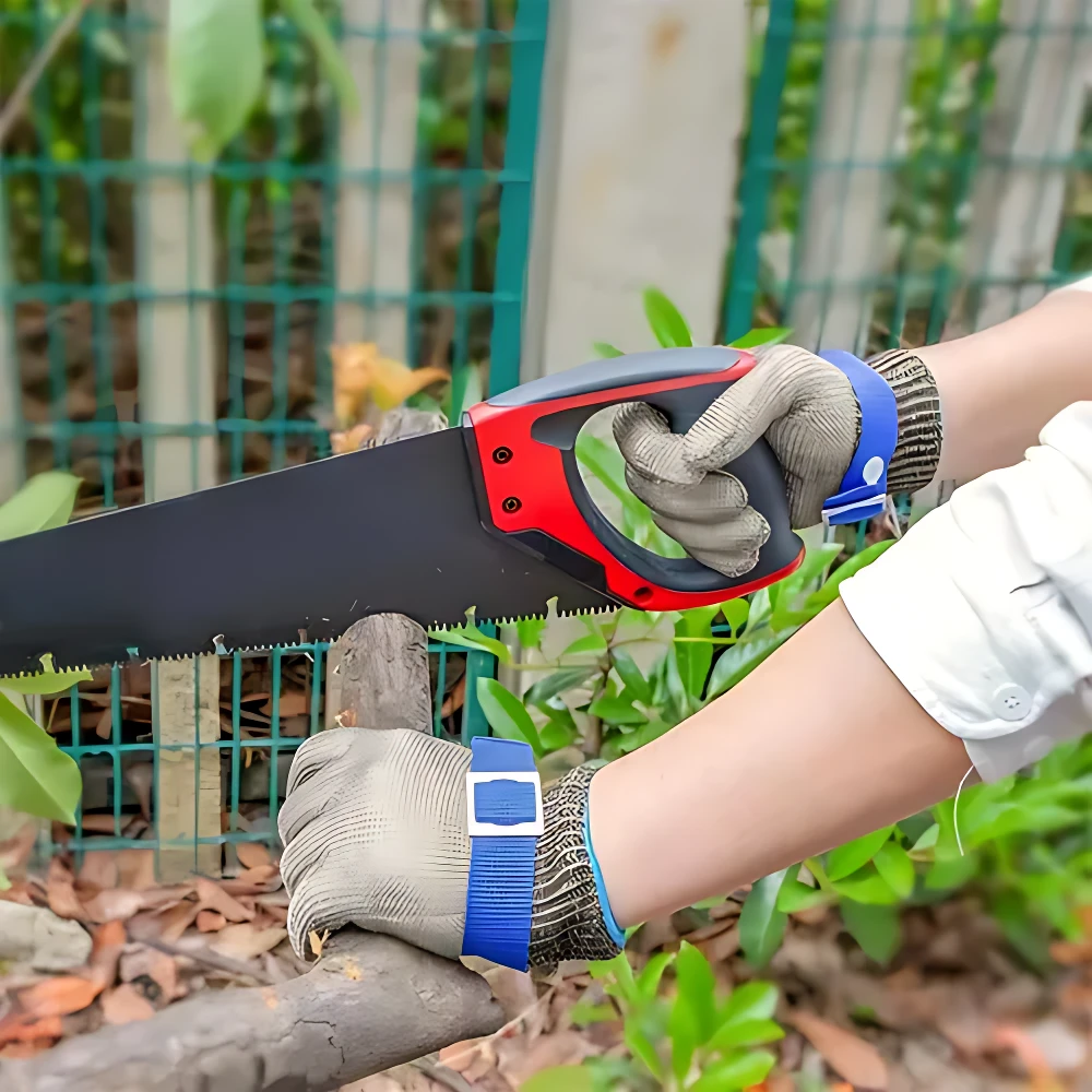 Guante de seguridad en malla de acero inoxidable con refuerzo azul, usado mientras se corta madera con sierra manual en jardín.