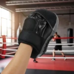 Guante de boxeo negro con cuero PU y espuma densa, mostrando protección en muñeca y diseño ergonómico para entrenamiento.