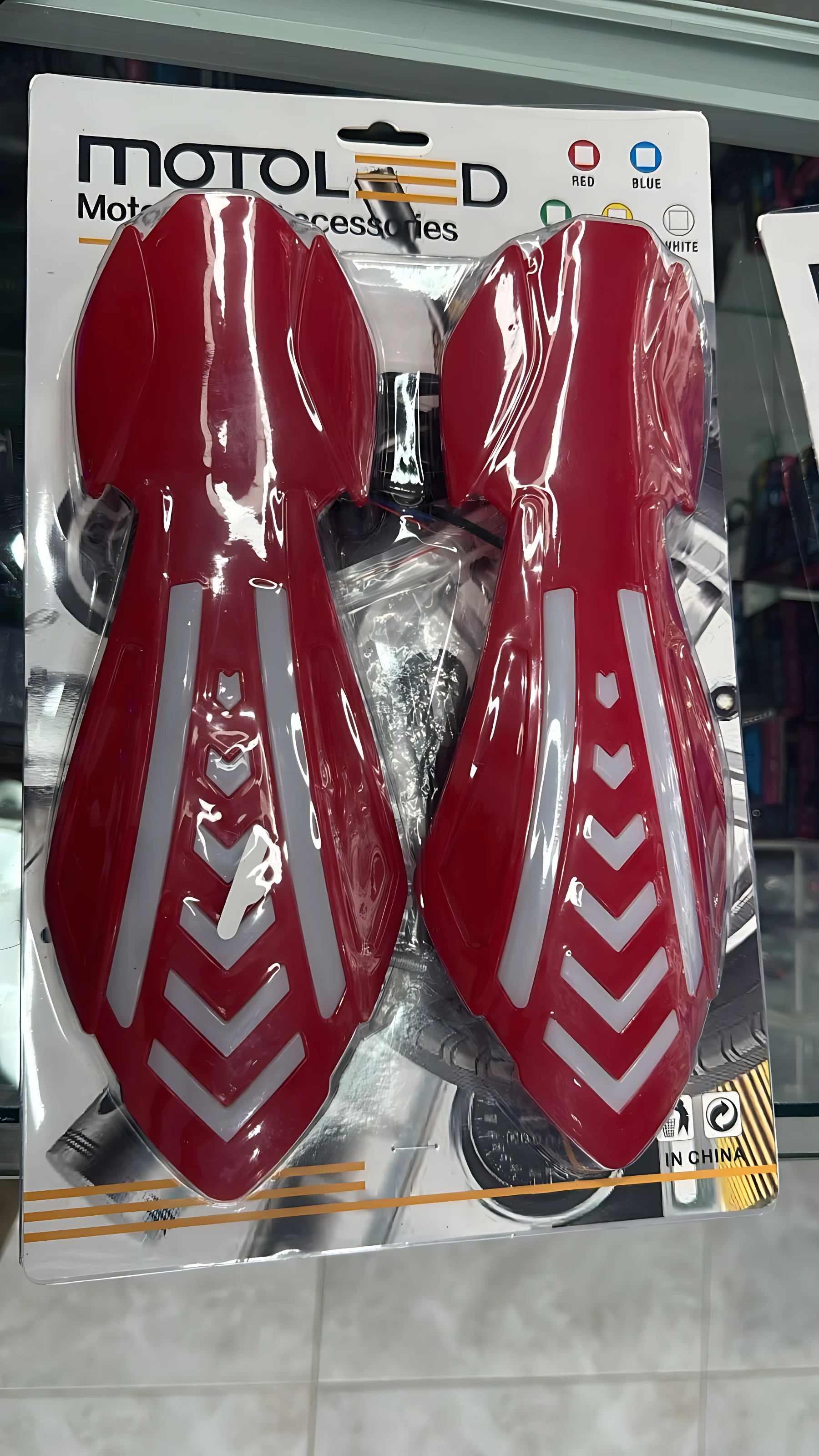 Cortavientos rojo con luces LED integradas, diseño ergonómico con detalles en blanco, empaquetado para manillares de motocicleta.