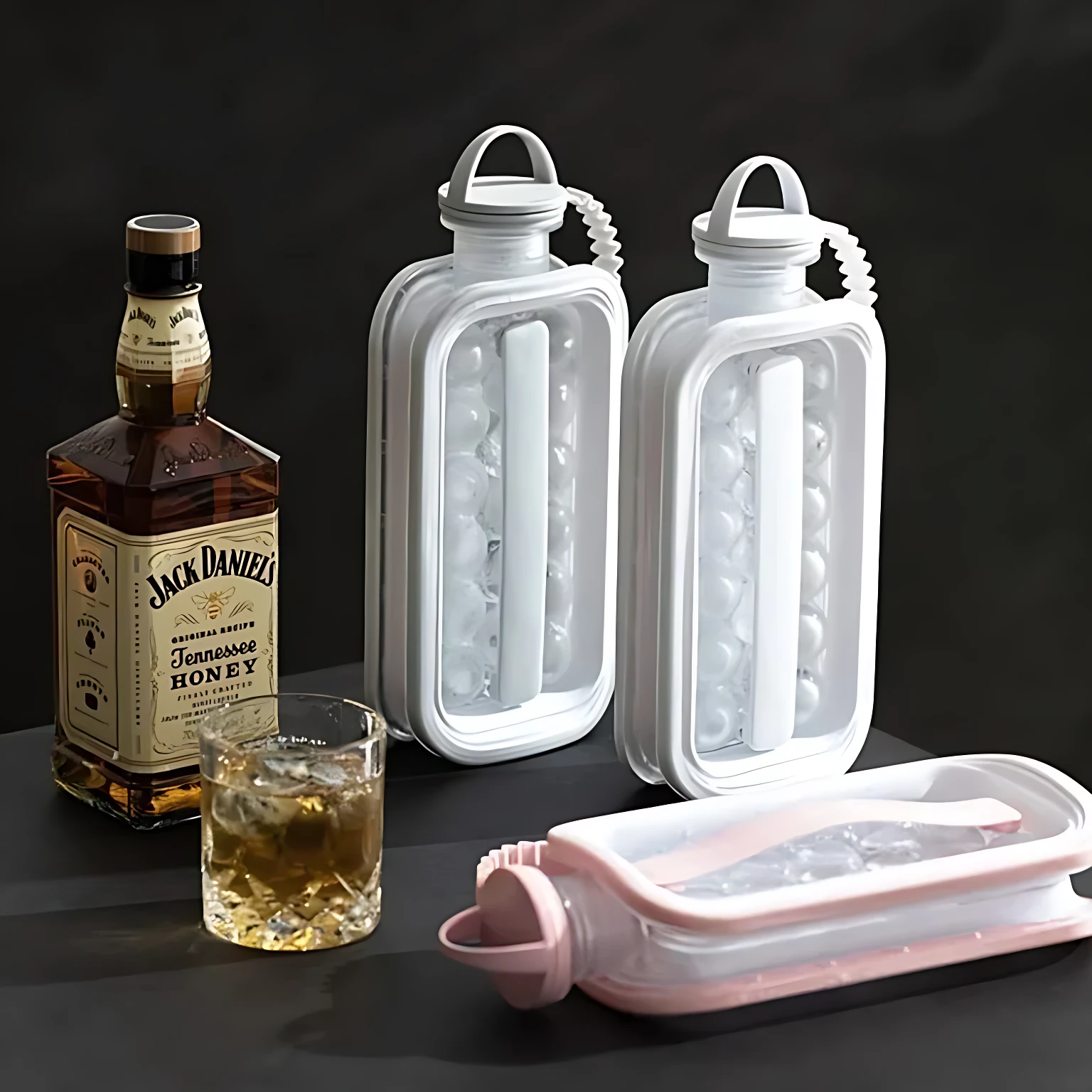 Dos hieleras portátiles blancas con asas, una abierta mostrando hielo y otra cerrada, junto a una tercera en color rosa abierta, acompañadas de una botella de Jack Daniel’s y un vaso con bebida.