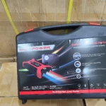Iniciador de carro rojo en maleta negra con luces LED, puerto USB y compresor integrado para arrancar motores e inflar llantas.