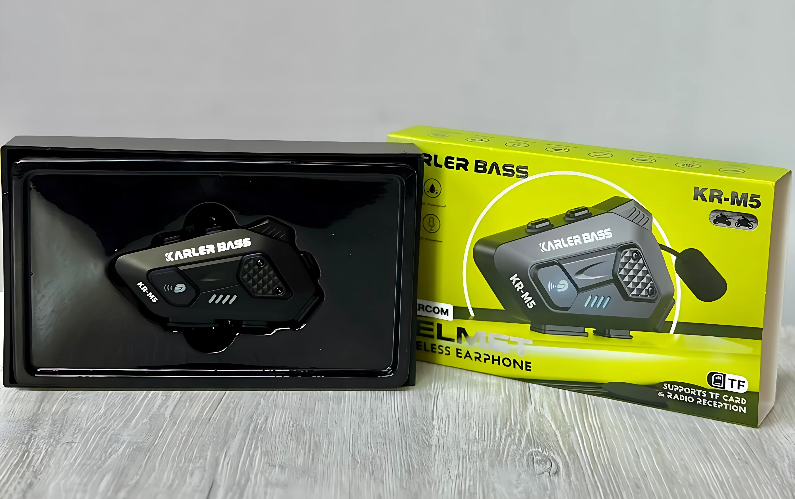 Intercomunicador Karler Bass KR-M5 en caja abierta, mostrando el dispositivo negro con micrófono integrado y cable de audio, sobre fondo gris claro.