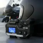 Intercomunicador Bluetooth KRM8 negro con pantalla azul, micrófono y controles táctiles, montado en casco de moto.
