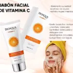 Tubo de jabón facial Bioaqua Vitamina C de 100g, con diseño naranja y texto en español, acompañado de su caja y modelo aplicando producto en rostro.
