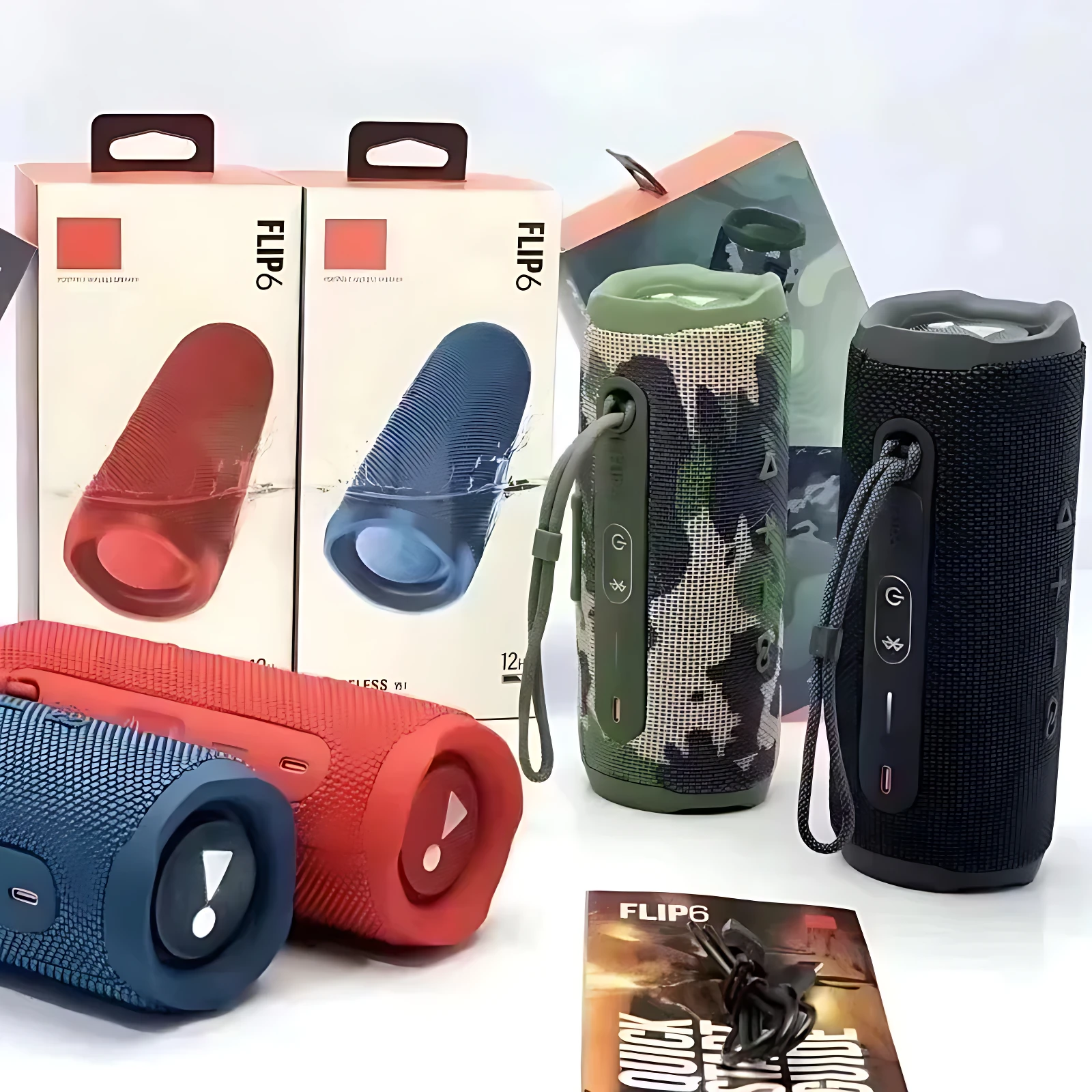 Cuatro altavoces Bluetooth JBL Flip 6 en colores rojo, azul, verde camuflado y negro, con empaques y accesorios visibles.
