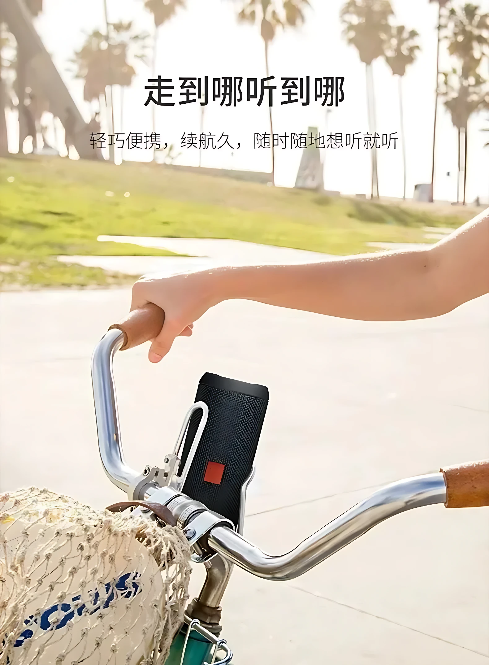 Altavoz JBL Flip 6 negro montado en manillar de bicicleta, con bolsa de malla beige y fondo de parque soleado.