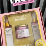 Kit de cuidado corporal Truly en caja rosa con tres productos: aceite de afeitado, crema corporal y loción corporal, todos con etiquetas blancas y doradas.