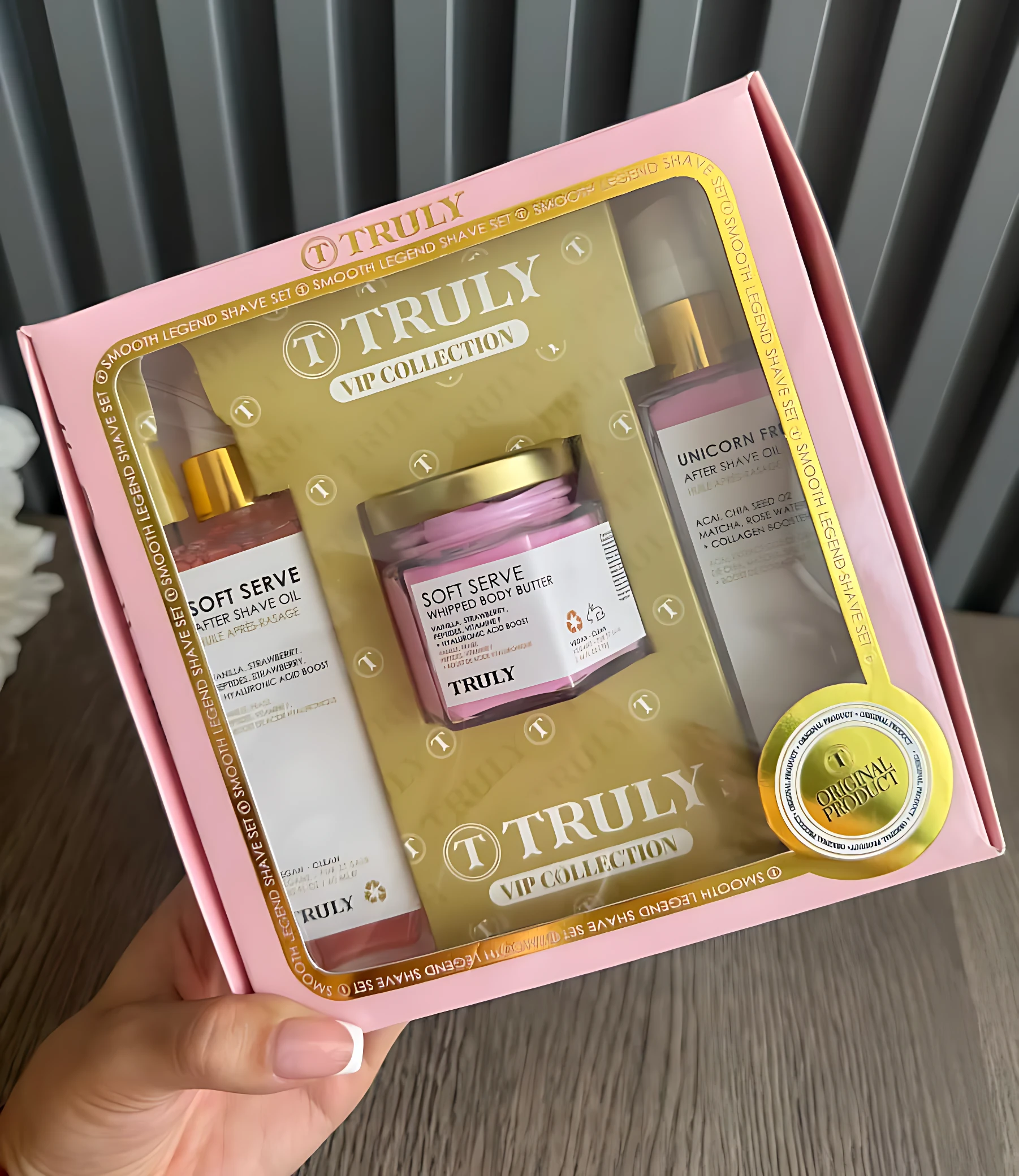 Kit de cuidado corporal Truly en caja rosa con tres productos: aceite de cuerpo, crema hidratante y loción corporal, todos con etiquetas doradas y tapas metálicas.