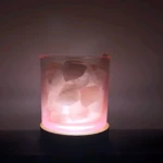 Lámpara aromatizante de vidrio con cristales de sal natural, luz rosada suave, base circular, ambiente relajante.