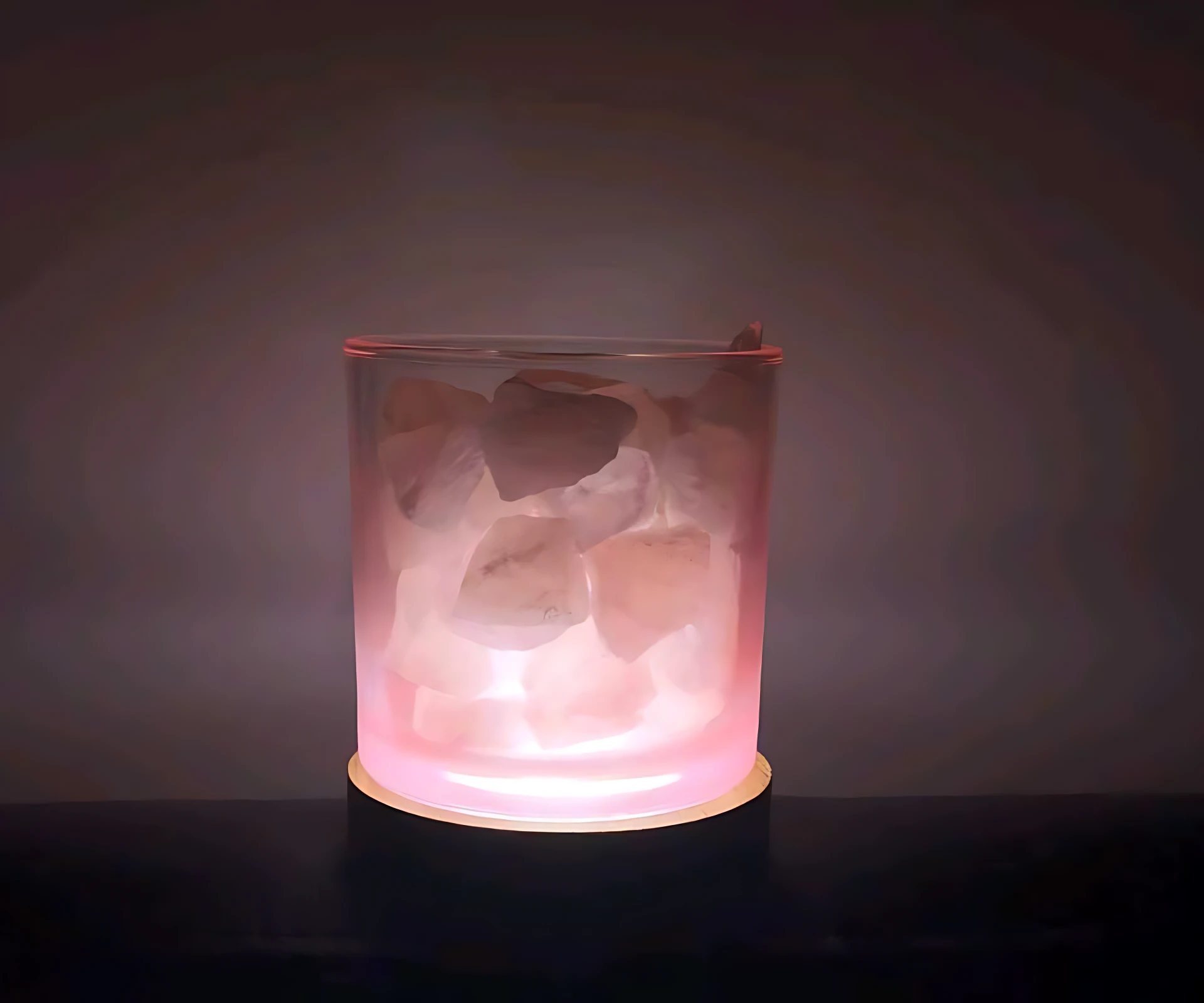 Lámpara aromatizante de vidrio con cristales de sal natural, luz rosada suave, base circular, ambiente relajante.