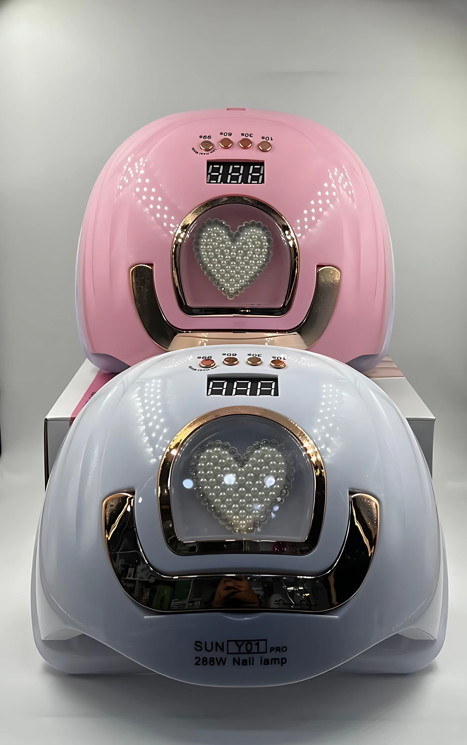 Lámpara LED para uñas en color rosa con diseño de corazón en la parte frontal, mostrando el panel de control digital y la base de la unidad.