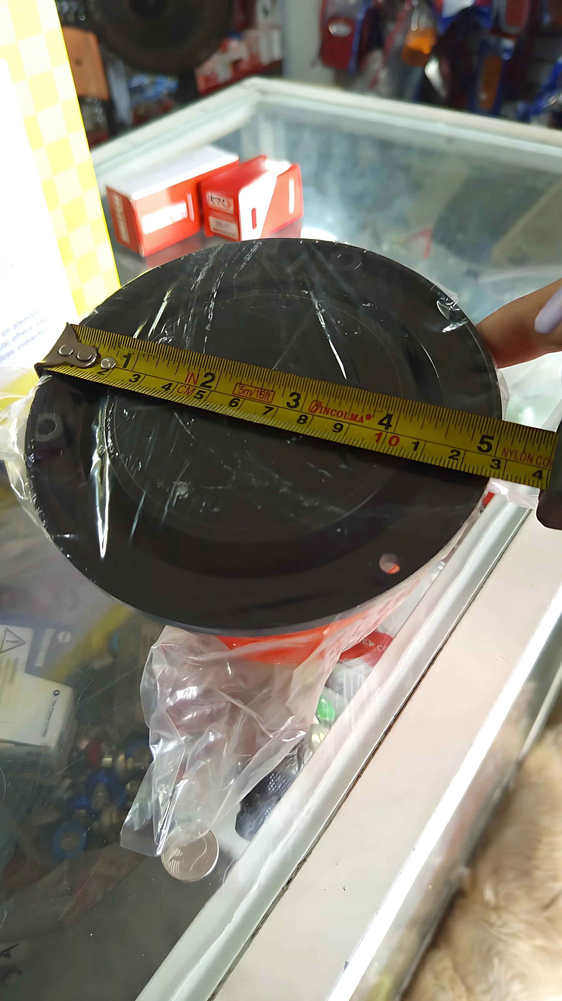 Licuadora inmantada negra con cinta métrica mostrando diámetro de 15 cm, sobre mostrador de tienda.