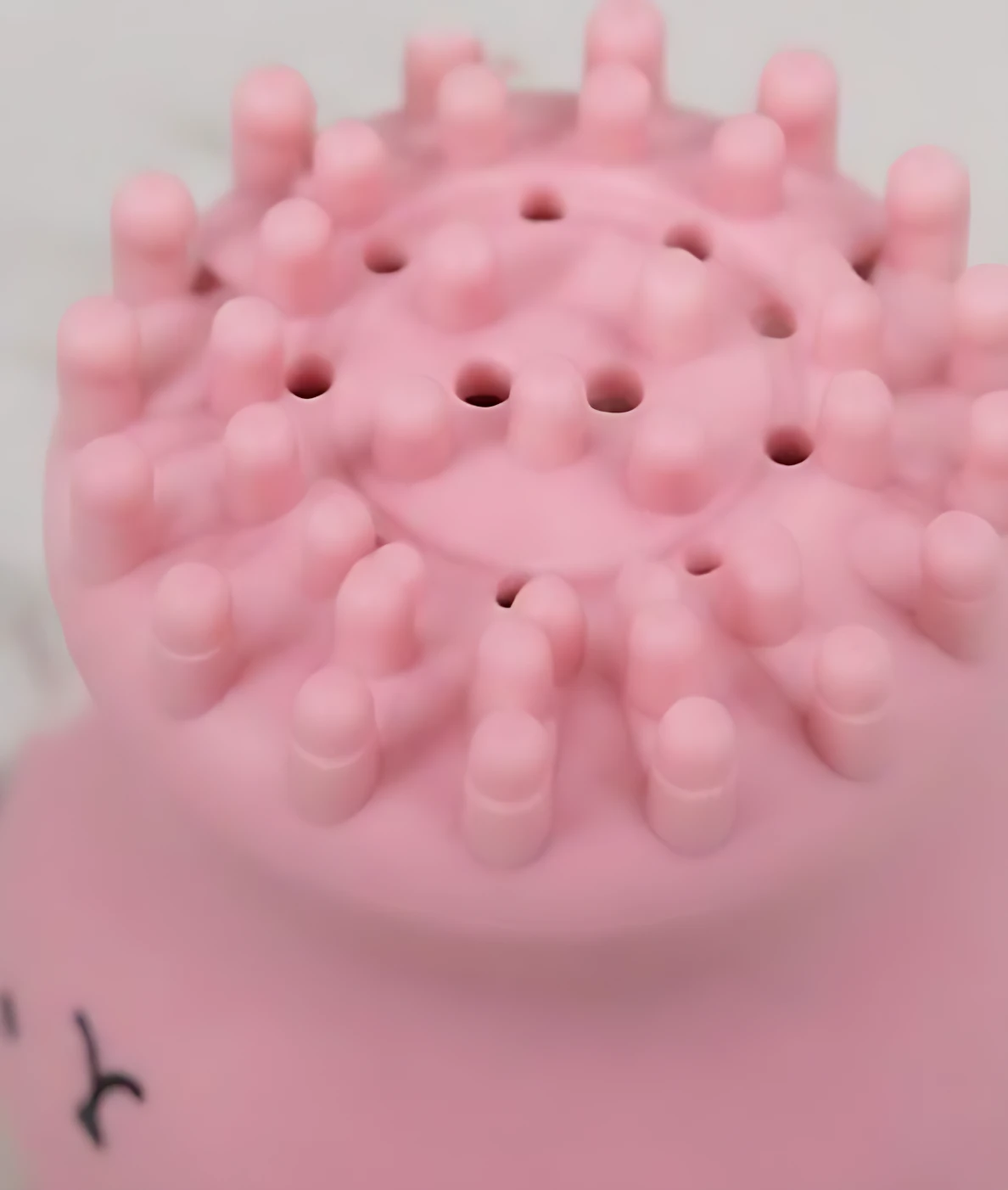 Vista superior de limpiador facial de silicona rosa con púas redondeadas y orificios centrales, diseñado para masaje y limpieza profunda.