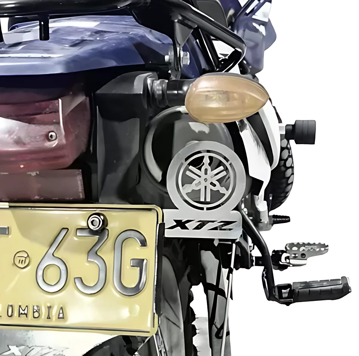 Porta placa XTZ 3D en color negro con logo Yamaha, instalado en la parte trasera de una motocicleta azul, protegiendo la matrícula amarilla con número 63G y texto COLOMBIA.