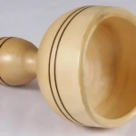 Copa sueca de maderoterapia ergonómica en madera clara con detalles en negro, vista lateral mostrando su forma ovalada y textura pulida.