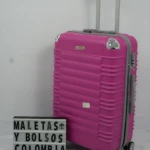 Maleta rígida rosa con ruedas giratorias y asa telescópica, junto a un letrero que dice "MALETAS Y BOLSOS COLOMBIA".