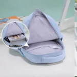 Mochila escolar azul claro de gran capacidad, con compartimento principal abierto mostrando interior acolchado y espacio para portátil de 15.6 pulgadas.