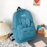 Morral azul con diseño de conejo dormido, seis bolsillos organizadores y etiqueta 'FASHION', ideal para equipaje escolar.