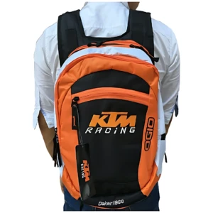 Mochila KTM Racing en naranja y negro, vista trasera con logo frontal y etiqueta colgante. Ideal para uso deportivo o urbano.