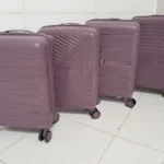 Cuatro maletas Ultra Flex 22 en tono lila, de polipropileno resistente, con ruedas giratorias y diseño estructurado, dispuestas en fila sobre suelo blanco.