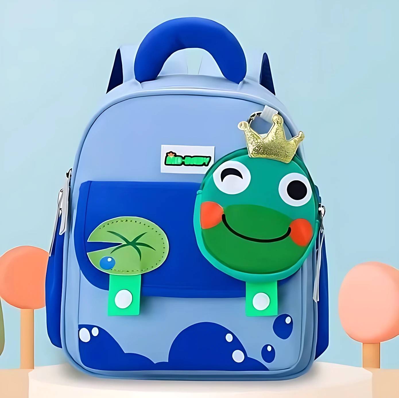 Mochila escolar infantil azul con diseño de rana sonriente y corona dorada, ideal para niños pequeños.