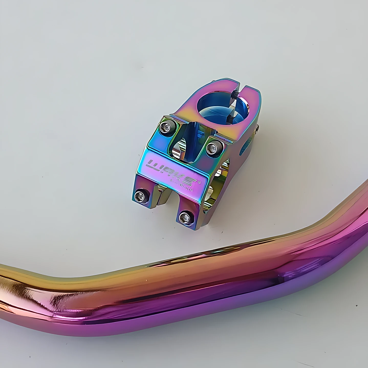 Manubrio de aluminio con acabado tornasol iridiscente, diseñado para motos naked. Incluye soporte de tuerca y tornillos visibles.