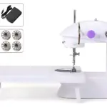 Máquina de coser mini portátil blanca con detalles morados, incluye accesorios como pedal, puntas y cable de alimentación.