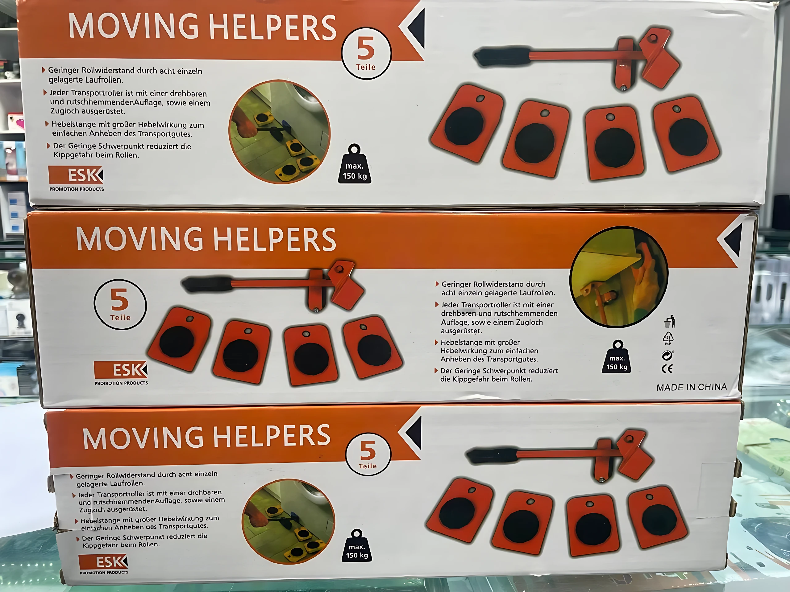 Caja de tres unidades de la máquina ergonómica para levantar muebles, marca ESKK, color naranja y negro, con ilustraciones de uso y especificaciones técnicas visibles.